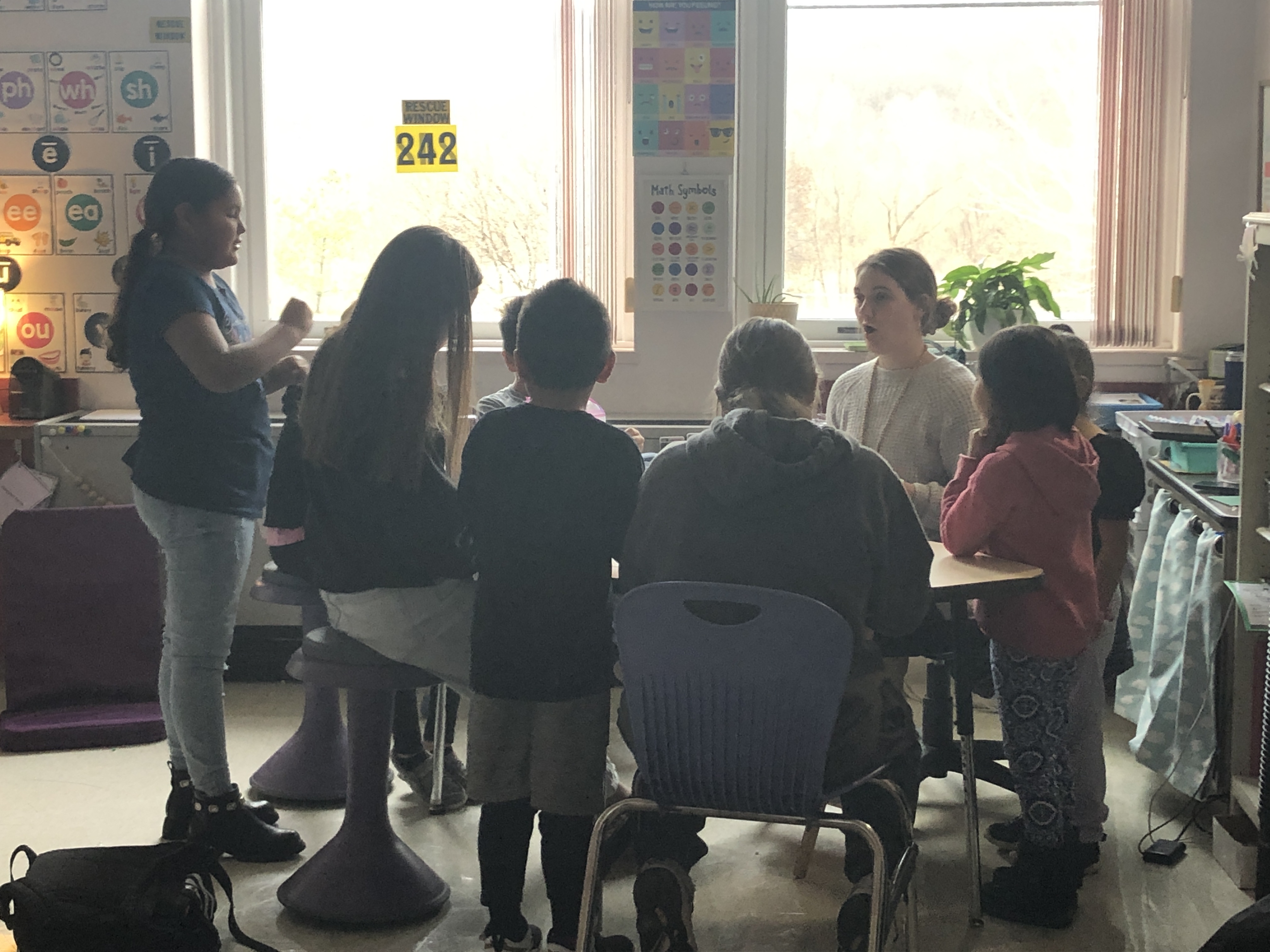 students gathered round table listening to instructions